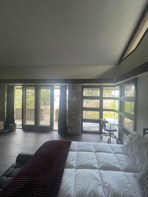 Une chambre avec un grand lit, un bureau et une vue par les fenêtres.