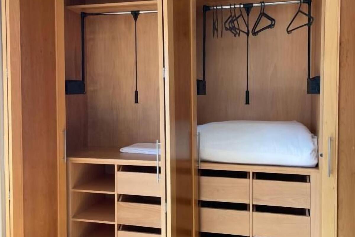 Un armario de madera con varios compartimentos, incluyendo espacio para colgar y cajones.