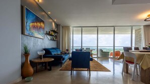 A modern living room with a sofa, chairs, a dining table, and a large window offering a view. - Waterfront escape w/ pool & BBQ grill (Cartagena de Indias)
