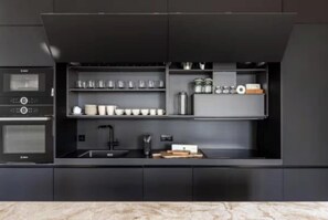 Una cocina moderna con electrodomésticos integrados, incluyendo una estufa y horno, y una encimera con estantes de almacenamiento.