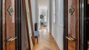 Un pasillo con puertas de madera, suelo de espiga y un banco.