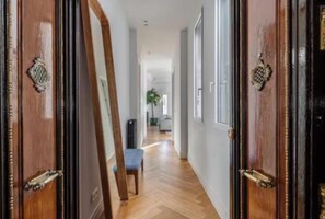 Un pasillo con puertas de madera, suelo de espiga y un banco.