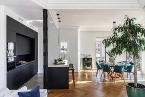 Una sala de estar moderna con un mueble de entretenimiento negro, una isla central y un comedor con sillas color turquesa.
