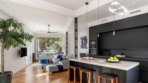 Una cocina moderna con una isla central, taburetes de bar y una planta grande en maceta.