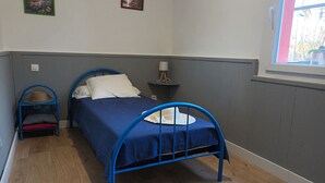 Una camera da letto con una struttura letto in metallo blu, un comodino con una lampada e un piccolo sgabello con un cappello sopra.