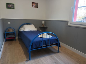 A bedroom with a blue metal bed frame, a bedside table with a lamp, and a small stool with a hat on it. - House in marseillan plage (Marseillan)