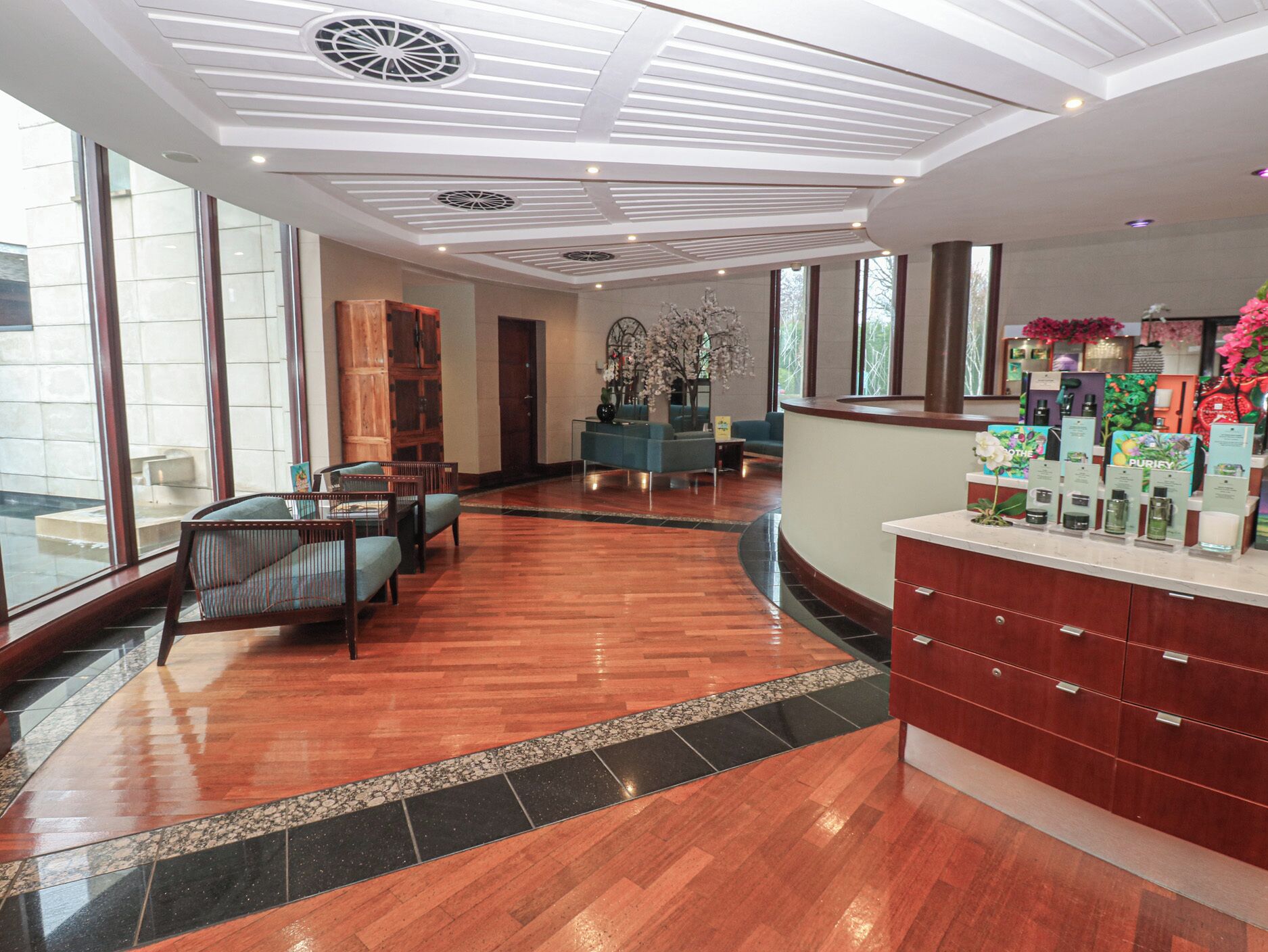 Eine großzügige Lobby mit Holzboden, einer Rezeption und Sitzbereichen.