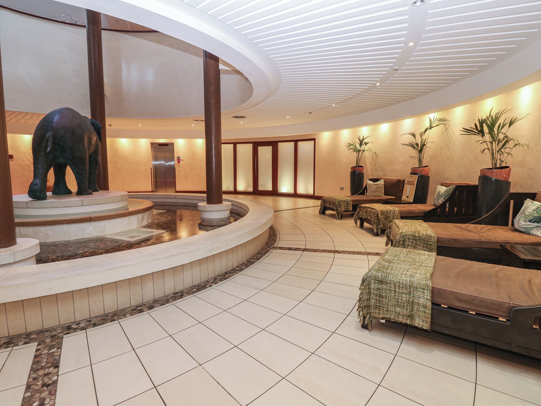 A lobby with a central water feature, seating area, and a reception desk.