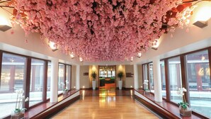 Un hall d’hôtel doté d’un plancher en bois, de grandes fenêtres et d’un plafond recouvert de fleurs roses.