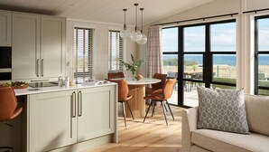 Une cuisine moderne avec un coin repas, de grandes fenêtres et une vue sur la mer.