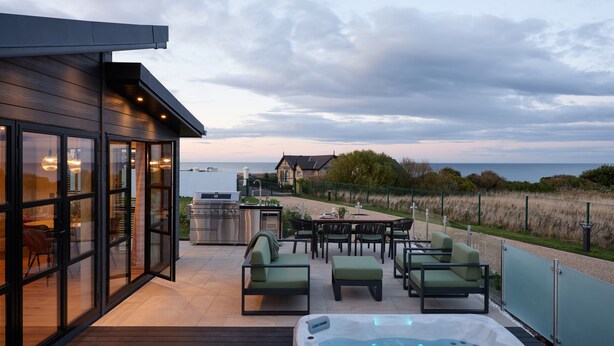 Une terrasse extérieure avec un jacuzzi, un espace salon et une vue sur la mer.