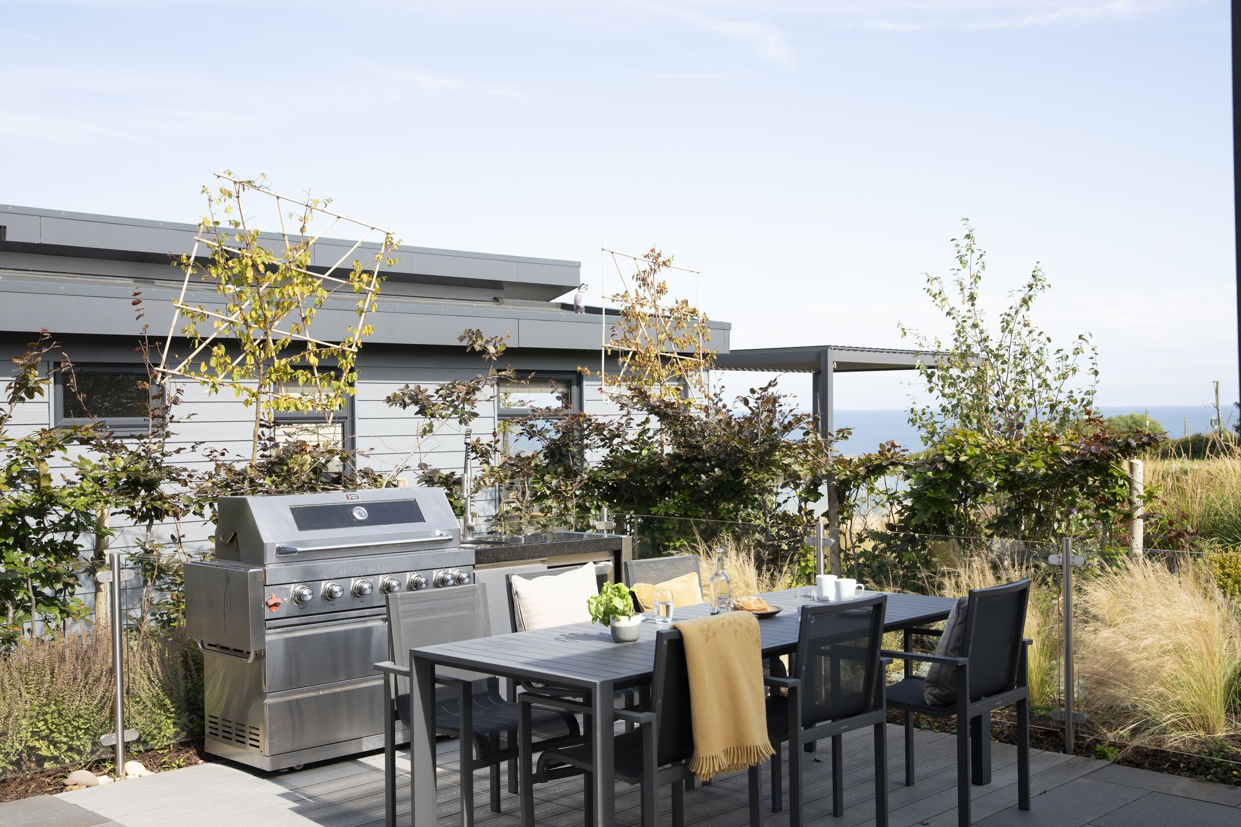 An outdoor patio with a grill, table, and chairs.