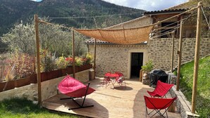 A patio with a table and chairs, a hanging chair, and a barbecue grill. - Gîte Métairie la Faurie in the heart of Drôme (Aurel)