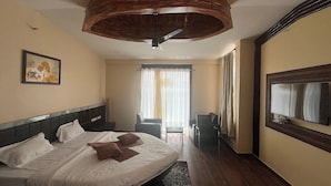 Une chambre d’hôtel équipée d’un lit, d’un bureau, d’une chaise, d’un grand miroir et d’un ventilateur de plafond.