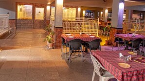 Un espace de restauration intérieur avec des tables et des chaises, un plafond haut et une vue sur l’intérieur du restaurant.