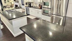 Una cocina moderna con armarios blancos, electrodomésticos de acero inoxidable y una encimera de granito negro.