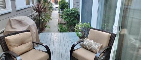 A balcony with two wicker chairs, a small potted plant, and a grill.