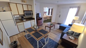A compact kitchen with a microwave, stove, and refrigerator. There is a dining area with a table and chairs. A sofa and a lamp are in the living area. - Sunny Escape 1st Floor Near Disney & Universal (Kissimmee)