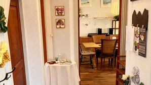 A hallway with a dining area, featuring a table set with a white tablecloth, chairs, and a small plant. - Struer Family House | 600m to Beach, Garden with Trampoline & Play Area (Struer)