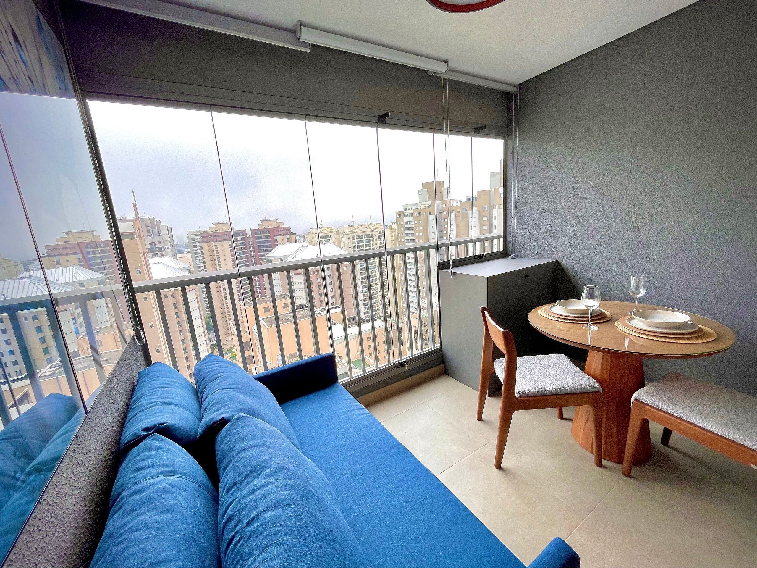 A balcony with a sofa and a dining table, both with cushions.