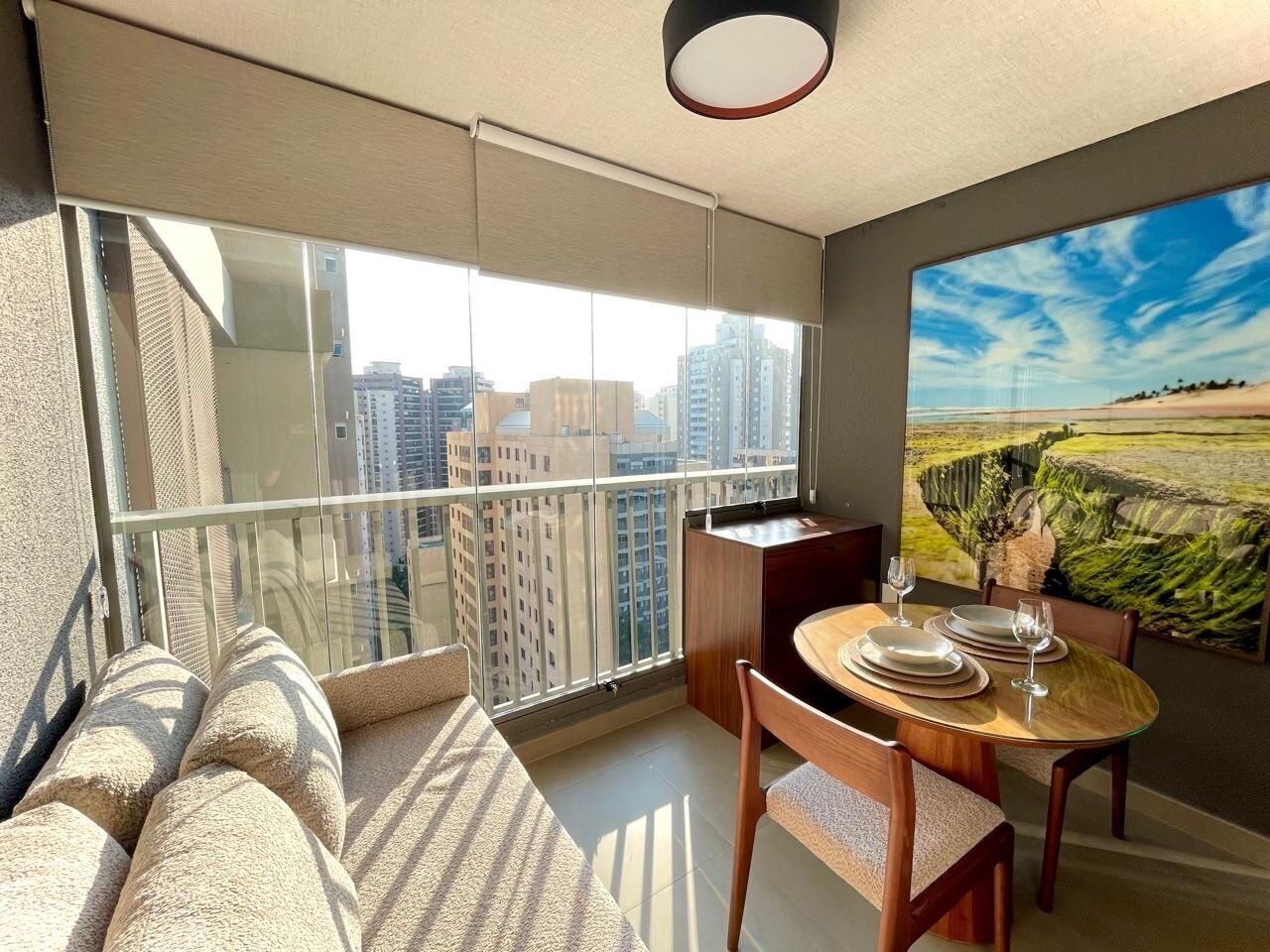 Un balcón con vistas a la ciudad, un comedor con una mesa para dos y un cuadro grande en la pared.