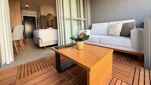 A modern hotel room with a bed, a sofa, a wooden coffee table, and a view of the outside. - Livinn - On Jurupis (São Paulo)