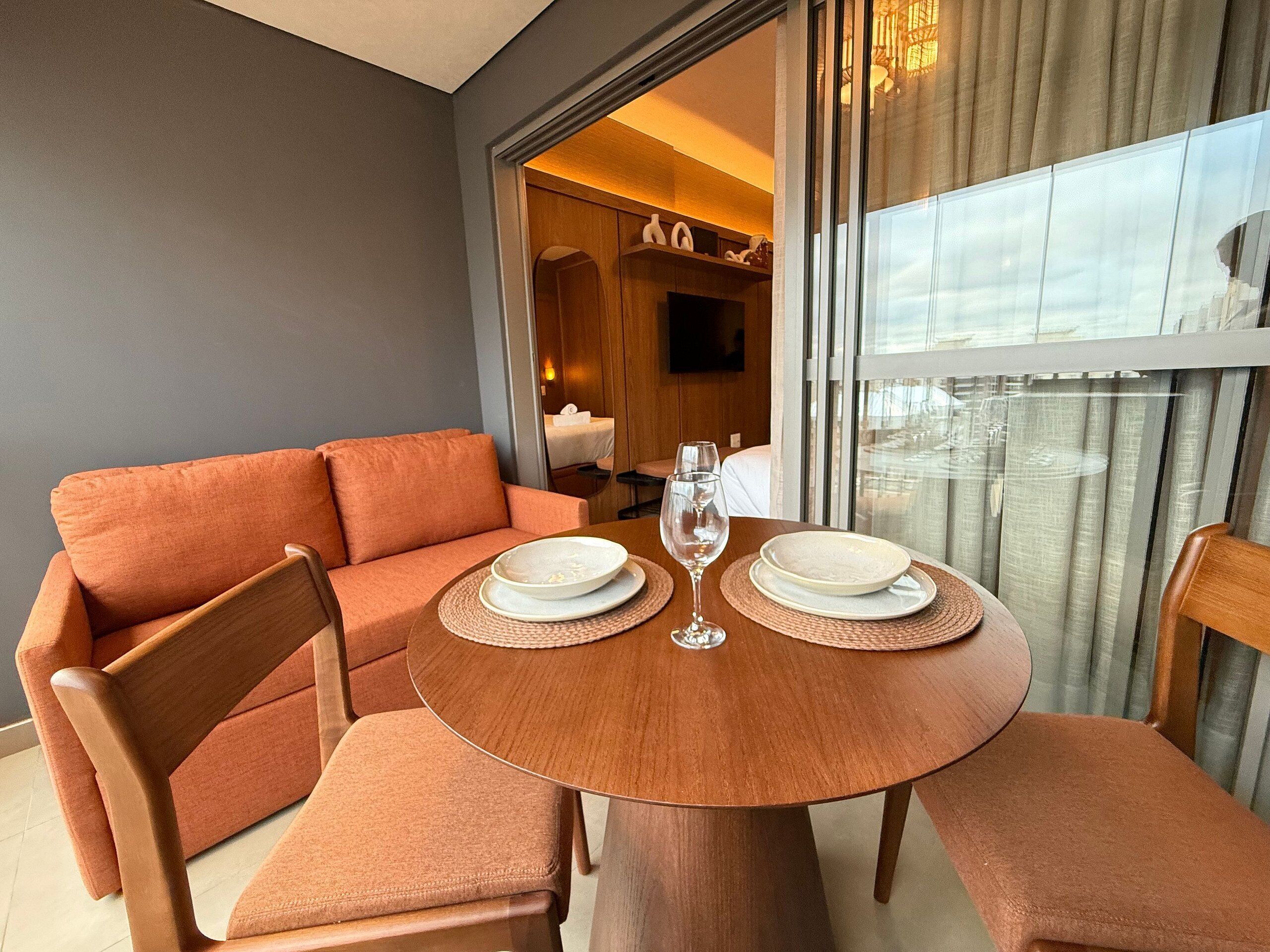 A dining area with a round table, orange upholstered sofa, and wooden chairs.