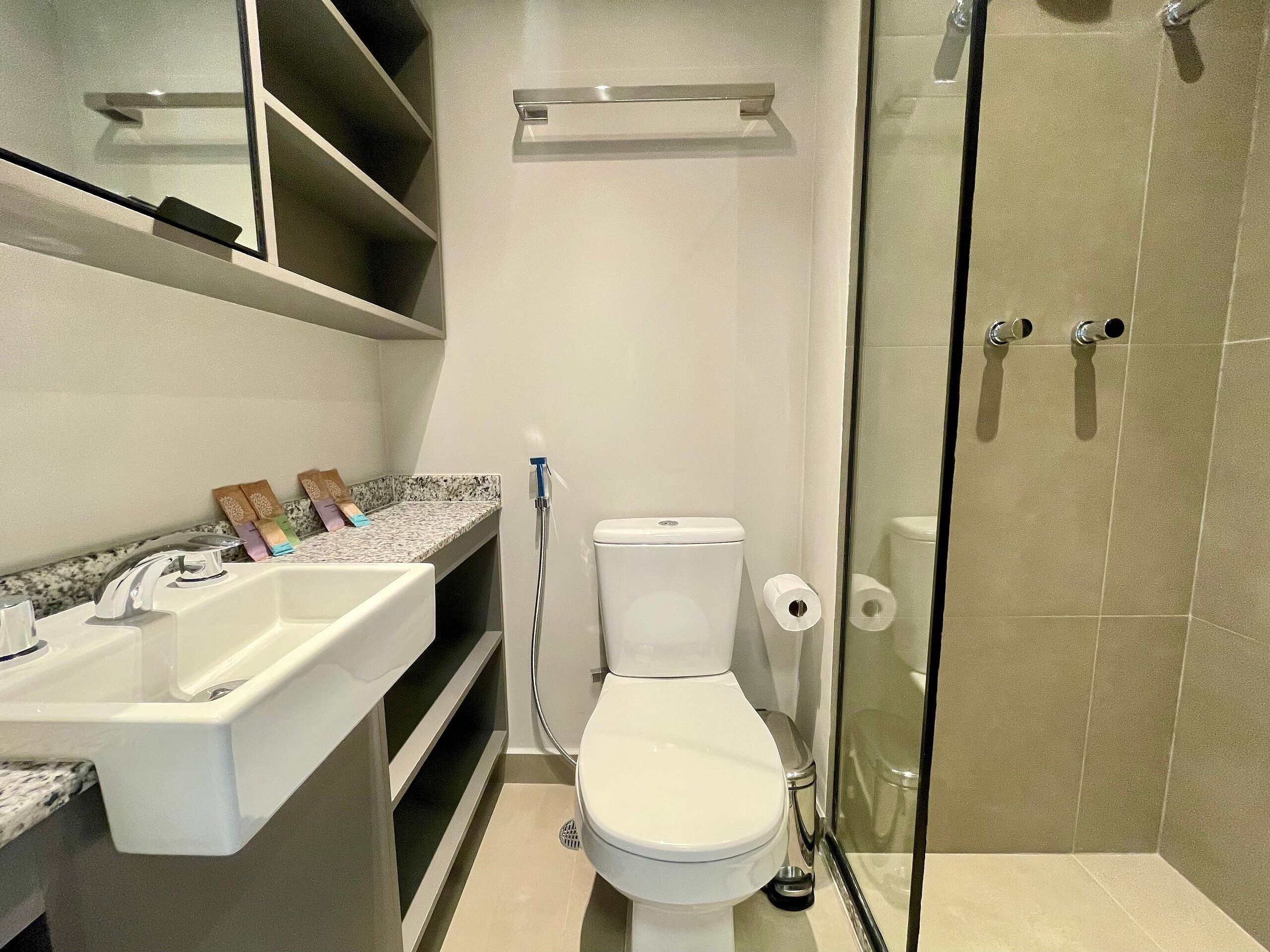 A bathroom with a white toilet, a sink with a marble countertop, and a glass shower enclosure.