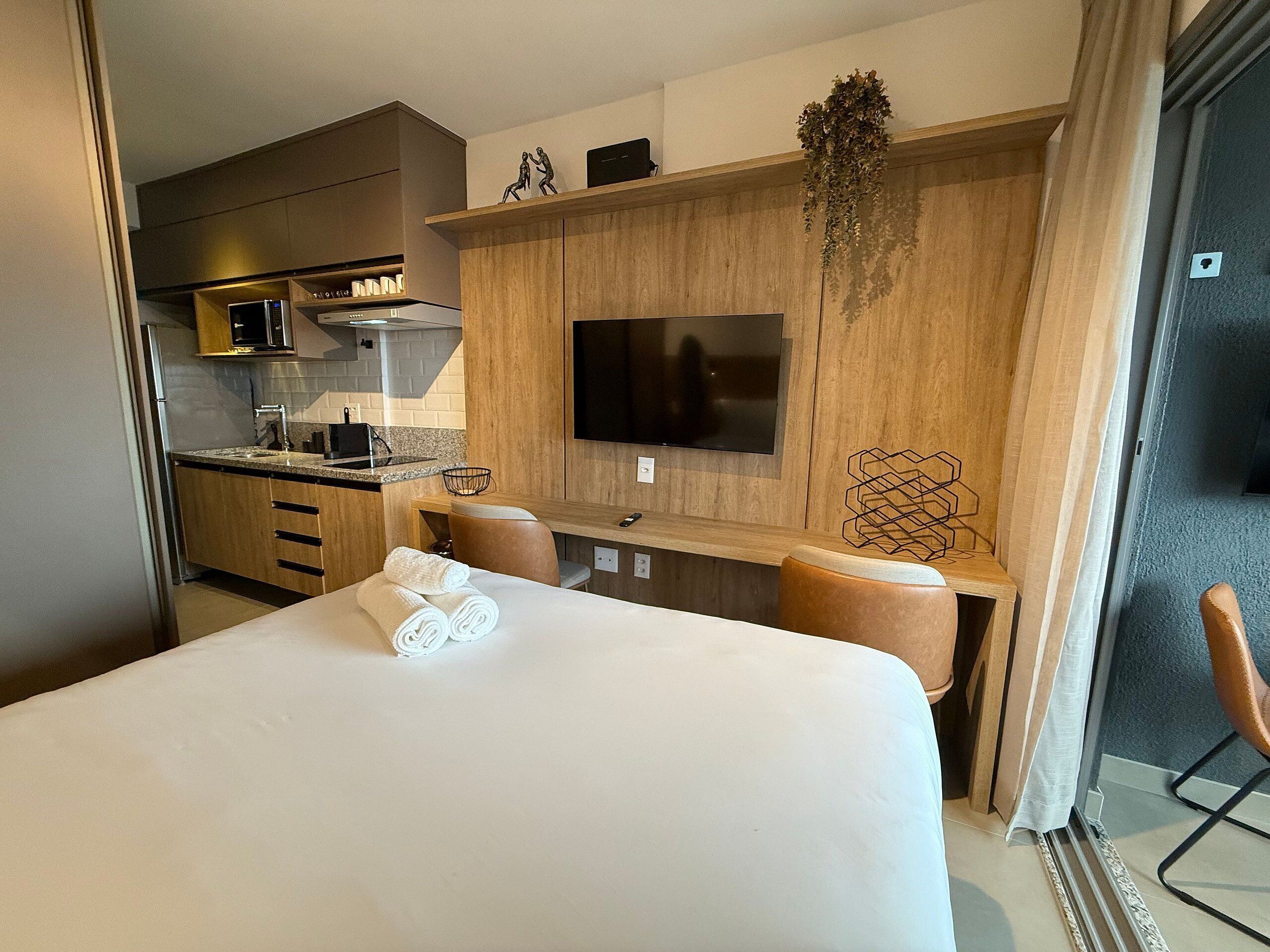 Een hotelkamer met een bed, bureau, televisie, keukenhoek en badkamer.