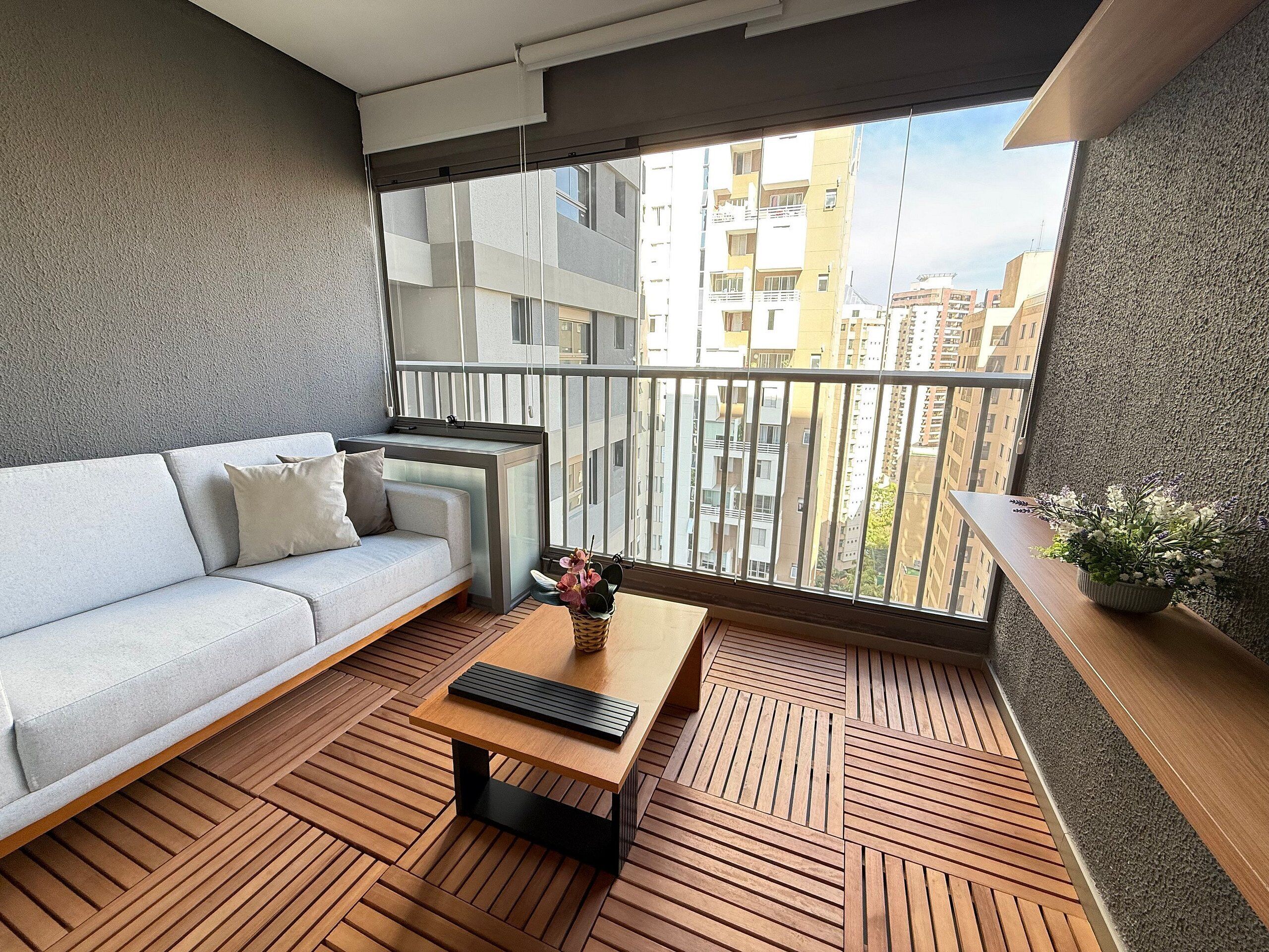 A balcony with a sofa, a coffee table, and a potted plant.