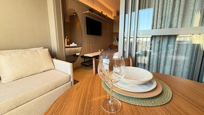 A modern hotel room with a wooden dining table, a glass wine glass, and a sofa. - Livinn - On Jurupis (São Paulo)