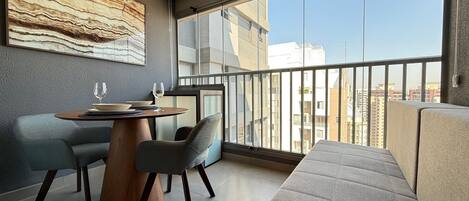 A modern living room with a dining area, large windows, and a city view.