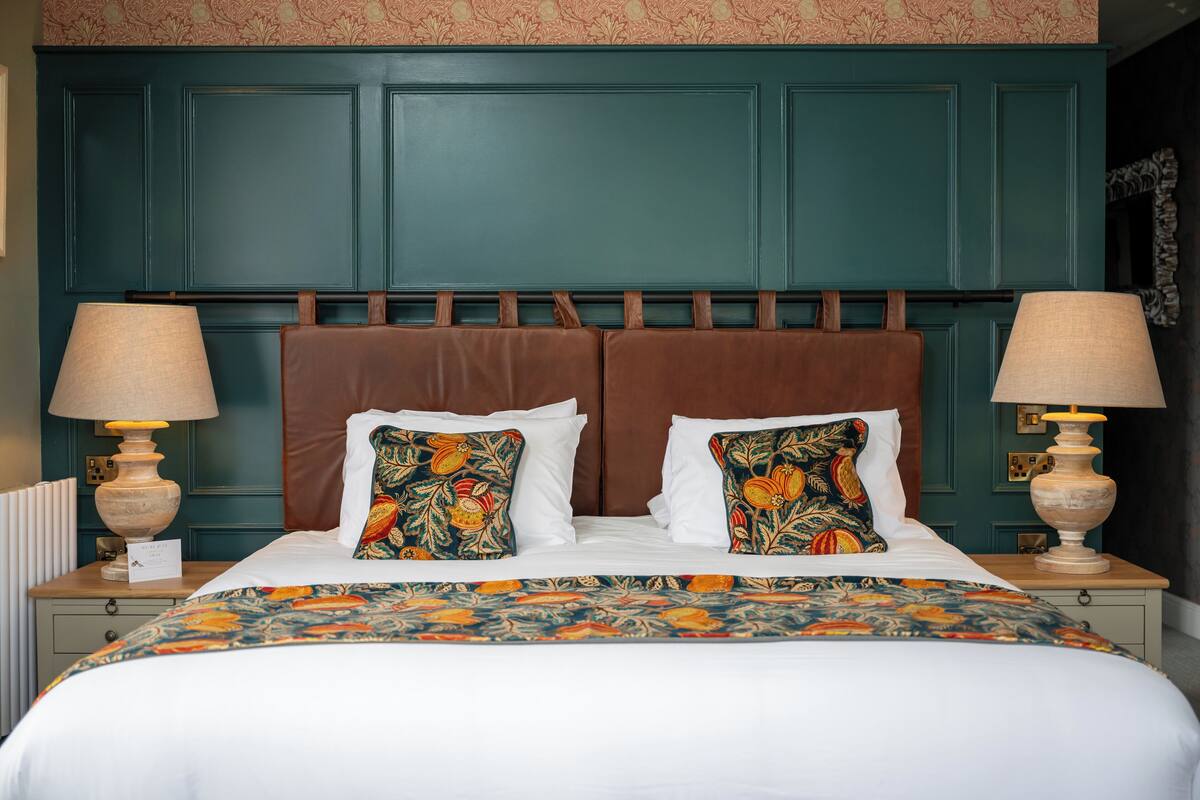 A neatly made bed with a floral bedspread, two decorative pillows, and two bedside lamps.