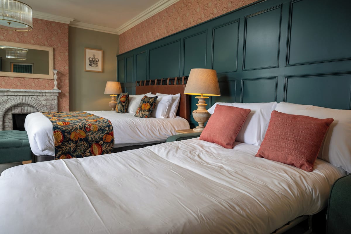 A hotel room with two beds, a fireplace, and a large window.