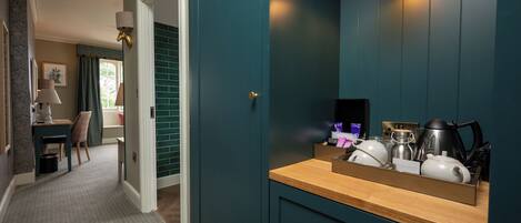 A hotel room with teal walls, a wooden counter, and a mirror.
