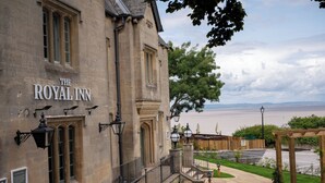 The Royal Inn, en historisk byggnad i sten med en imponerande entré, en välskött trädgård och utsikt över havet.