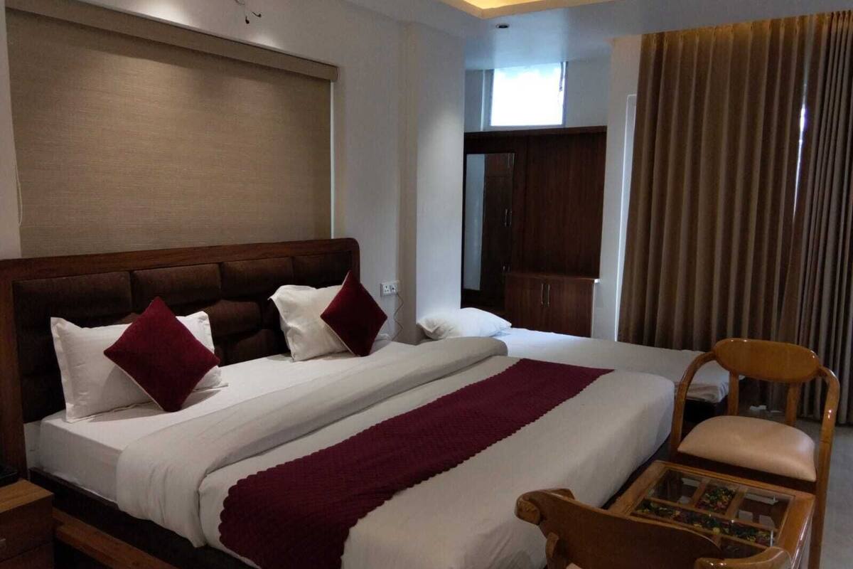 Ein Hotelzimmer mit einem großen Bett, einem hölzernen Kopfteil, einem Holzstuhl, einem kleinen Tisch und einem Schrank.