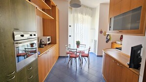 Eine kompakte Küche mit Essbereich, Holzschränken, einer Mikrowelle und einem Fernseher.