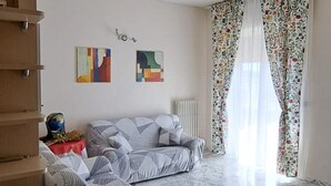 Ein Wohnzimmer mit zwei Sofas, einem Heizkörper und einem Fenster mit blumigen Vorhängen.