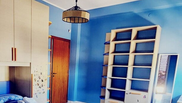 Ein Schlafzimmer mit Bett, Kleiderschrank, Regalen und Marmorboden.