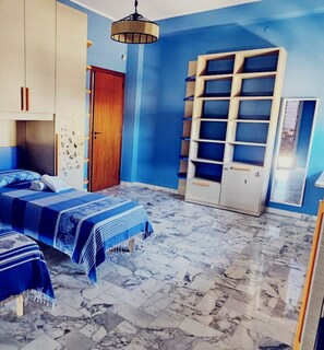 Un dormitorio con cama, armario, estantería y suelo de mármol.