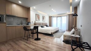 A modern hotel room with a kitchenette, a bed, a dining area, and a seating space. - Sleek Apartment in the Heart of Piraeus (Piraeus)