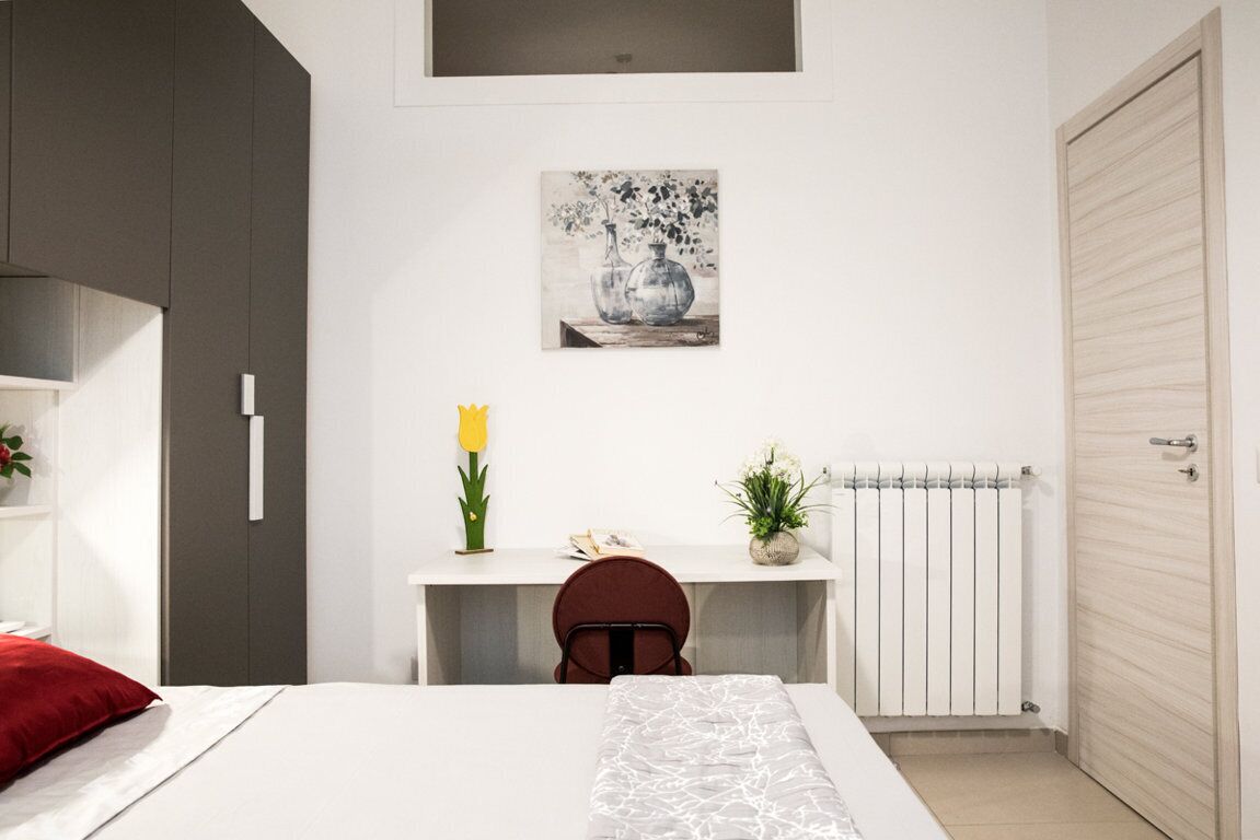 A modern bedroom with a bed, a desk, and a radiator.