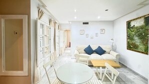 Un vaste espace de vie comprenant un canapé blanc, une table ronde en verre et une chaise blanche.
