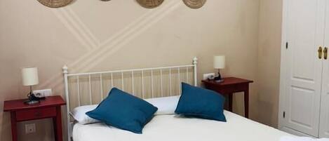 A bedroom with a bed, two nightstands, a wardrobe, and four wall decorations.