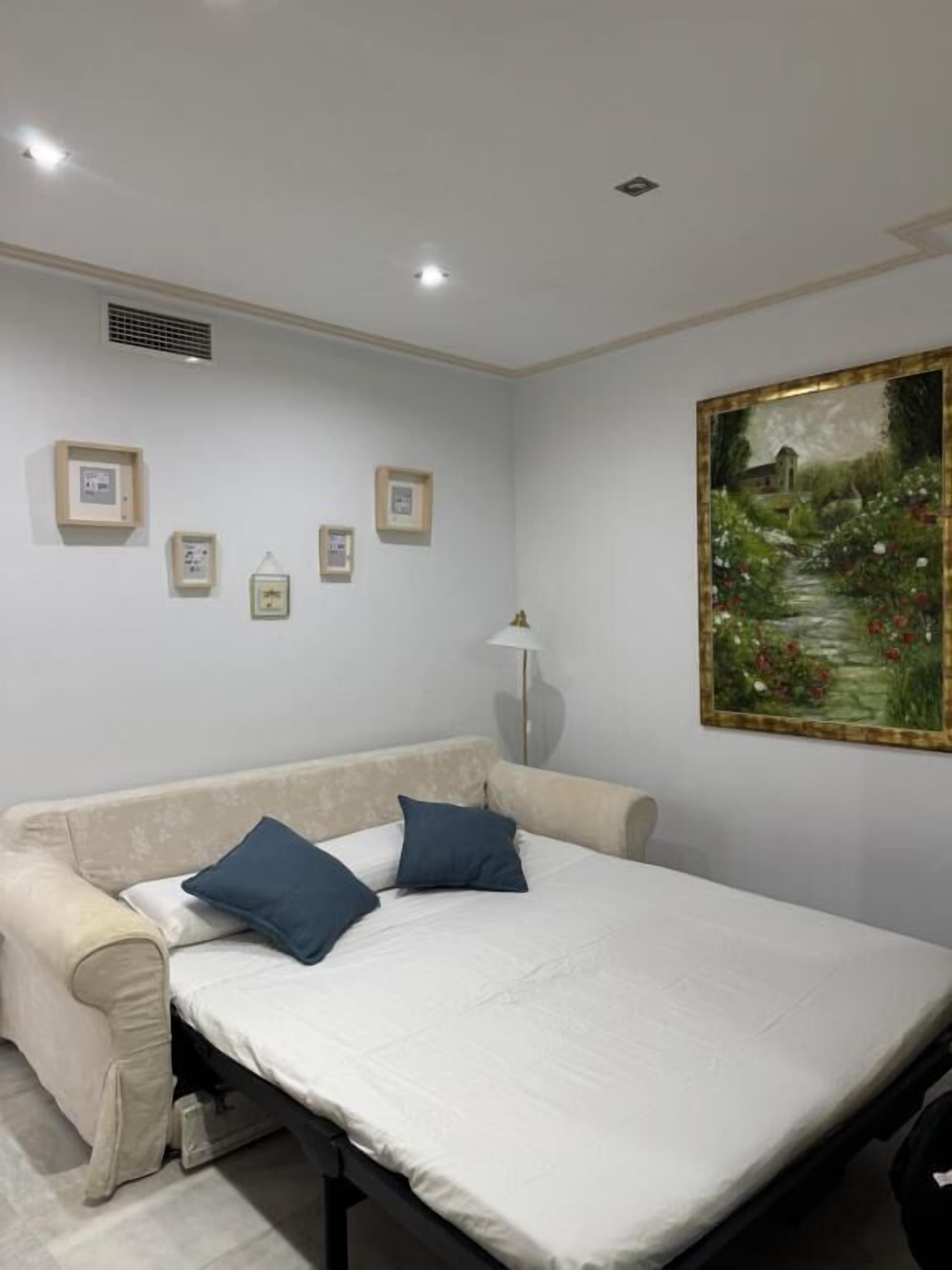 Quarto com cama, sofá, pintura e abajur.