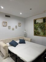 Un dormitorio con cama, sofá, un cuadro y una lámpara.