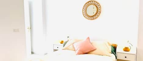 A hotel room with a bed, two bedside tables, a wall-mounted mirror, and a door.