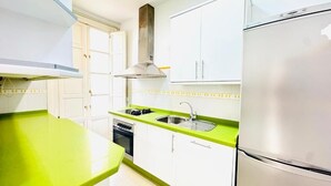 Une cuisine moderne avec des meubles blancs, un réfrigérateur en acier inoxydable et un plan de travail vert.