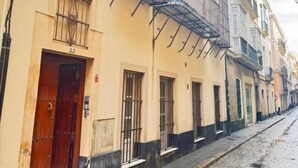 Une ruelle étroite pavée, bordée d’immeubles dotés de balcons ornés de garde-corps en métal.